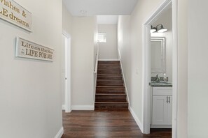 A hallway with a wooden staircase leading to a room with a bathroom. - Walk to Beach • Heated Pool • 3 King Beds • Boat Ramp • St. Augustine (St. Augustine)