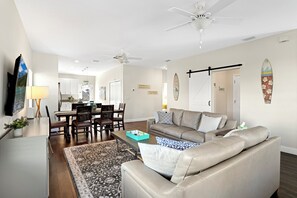 Uma sala de estar moderna com sofá, mesa de centro e área de jantar com cadeiras e mesa.
