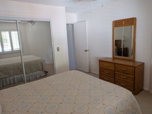 A bedroom with a bed, a dresser, a mirror, and a closet. - 2-bedroom condo in Flagstaff at Continental Country club. (Flagstaff)