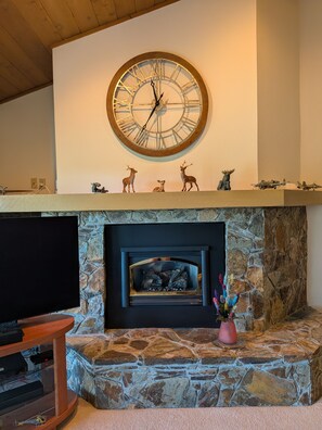 A stone fireplace with a clock above it, a television on the left, and decorative items on the mantel. - 2-bedroom condo in Flagstaff at Continental Country club. (Flagstaff)