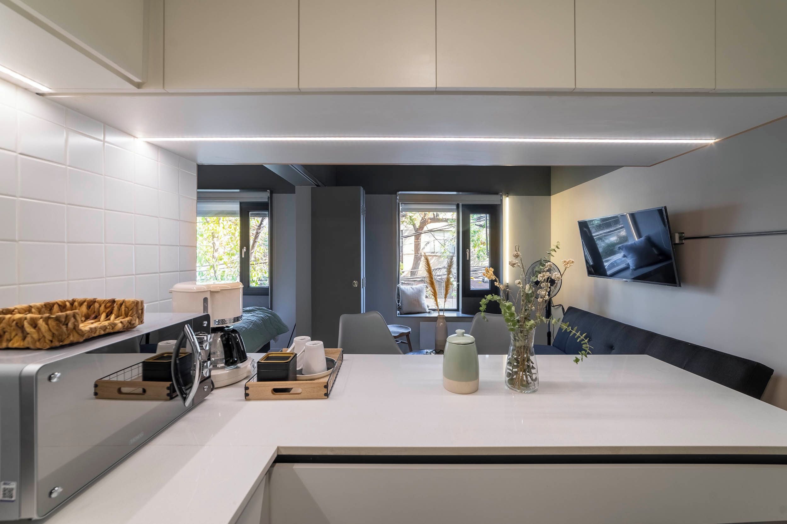 A modern kitchen with a built-in coffee maker, a toaster, and a kettle on the counter.