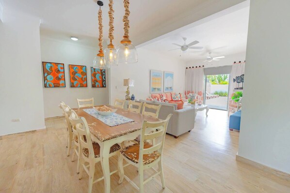 A dining area with a wooden table and chairs, a ceiling fan, and artwork on the walls.