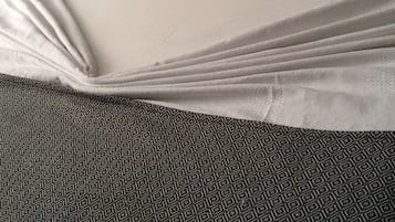 A bed with white and orange pillows, a patterned bedspread, and a geometric carpet.