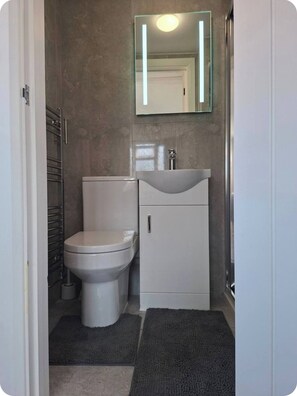 Ein Badezimmer mit Toilette, Waschbecken, Schrank und Spiegel.