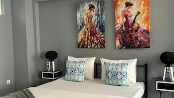 Un dormitorio moderno con una cama grande, dos mesitas de noche, una lámpara de techo negra y dos cuadros en la pared.