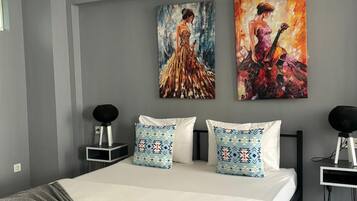 Un dormitorio moderno con una cama grande, dos mesitas de noche, una lámpara de techo negra y dos cuadros en la pared.