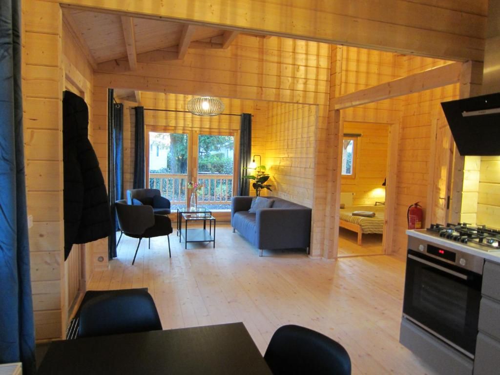 A wooden interior with a dining area, sofa, and kitchen.