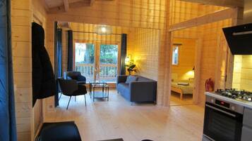 A wooden interior with a dining area, sofa, and kitchen.