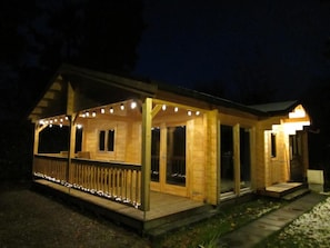 Una cabaña de madera con un porche cubierto y luces colgantes.