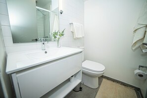 A bathroom with a white sink, mirror, and toilet. - Bright Studio · Selected Design (H11) (Providencia)