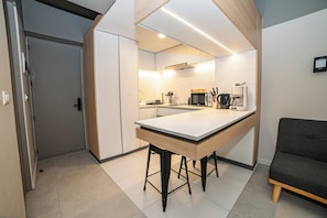 A modern kitchen with a central island, white cabinetry, and a built-in oven. - Bright Studio · Selected Design (H11) (Providencia)
