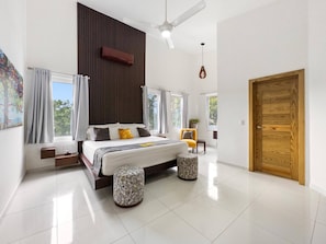 A modern bedroom with a large bed, a ceiling fan, and a wooden door. - Luxury Boss Villa in Sosua Hispaniola (Sosúa)
