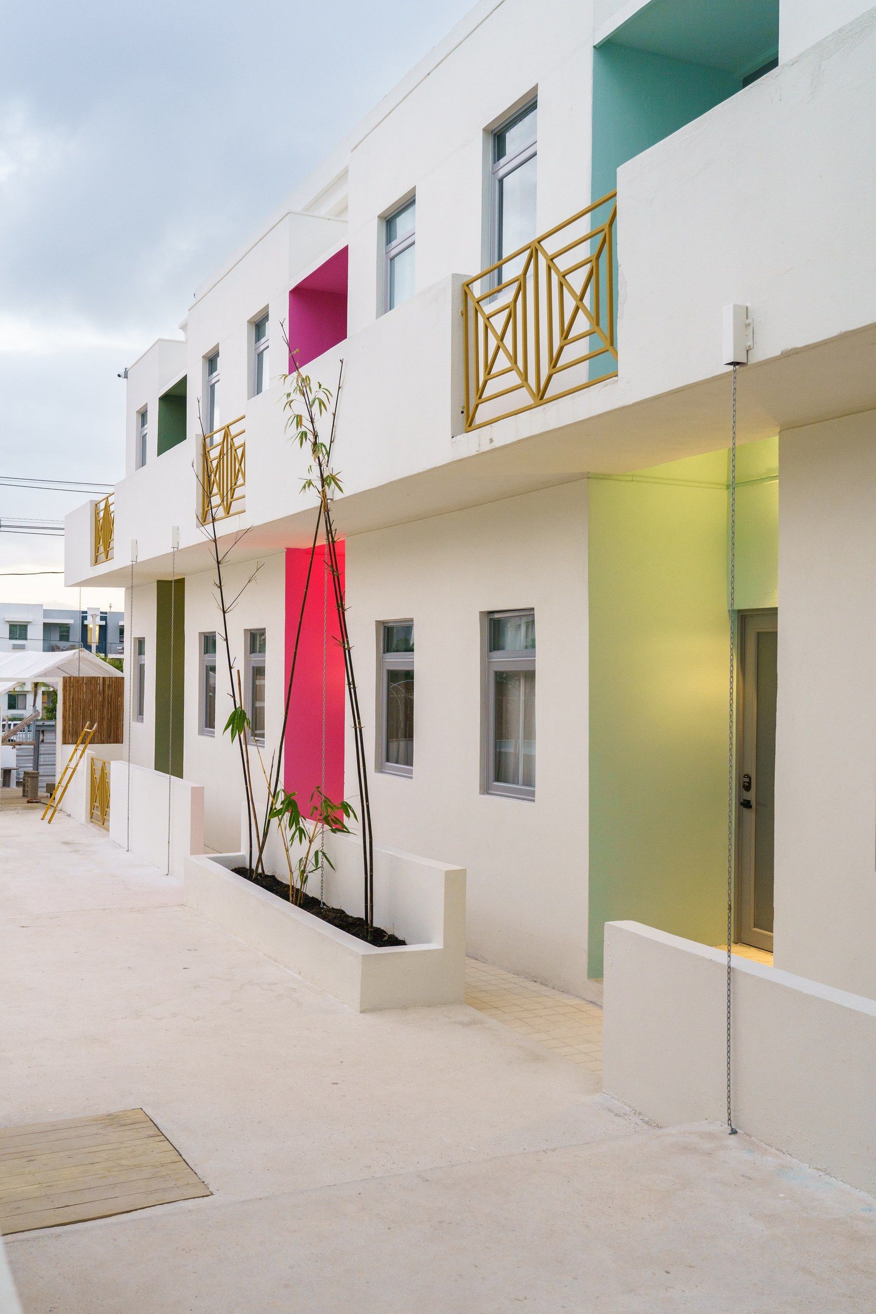 Un bâtiment moderne à la façade blanche, doté de nombreuses fenêtres et d’une entrée sécurisée par un portail.