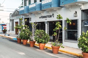 Um edifício com uma placa que diz 'LA FERRETERIA 200' e vários vasos de plantas ao longo da calçada.