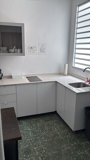A compact kitchen with a built-in stove, a sink, and a window with blinds. - Apt with Balcony Near Old San Juan-3 (San Juan)