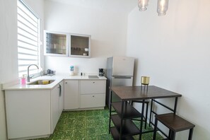 Eine kleine Küche mit Spüle, Schränken, einem Kühlschrank und einem Tisch mit einem Stuhl.