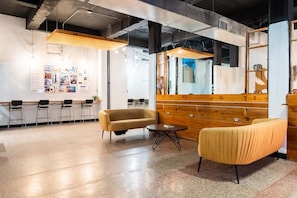Een modern interieur met een receptiebalie, een zithoek en een muur met informatieposters.