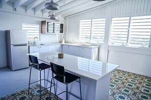 A kitchen with a central island, bar stools, a refrigerator, and a window with blinds. - Penthouse with Terrace, Near Old San Juan and Condado-5 (San Juan)