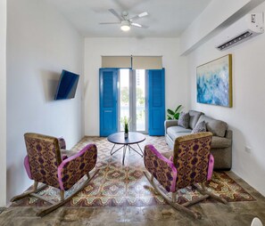 A living room with a sofa, two rocking chairs, a coffee table, and a ceiling fan. - Comfortable San Juan Apartment for 4 Guests - 4 (San Juan)