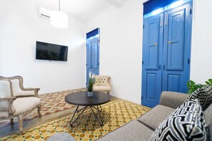 A living room with a sofa, armchair, and a coffee table with a potted plant. - Cozy City Escape | 1BR with AC & Full Kitchen - 6 (San Juan)