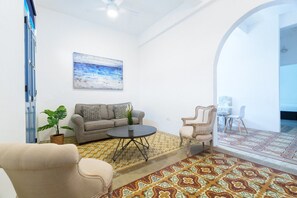A living room with a sofa, armchairs, a coffee table, and a potted plant.