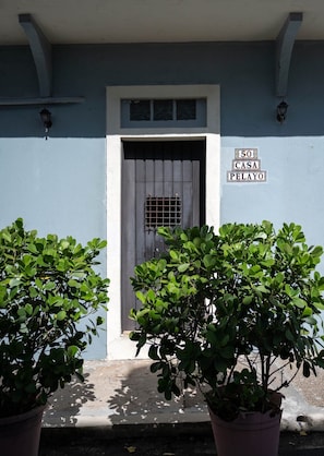Ein Gebäude mit blauer Fassade, einer grauen Tür und einem Schild mit der Aufschrift '50 CASA PELAYO'.