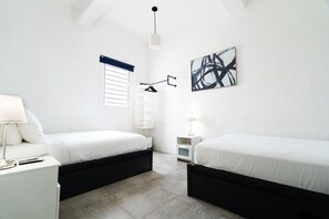Een moderne slaapkamer met twee bedden, een bureau en een nachtkastje.