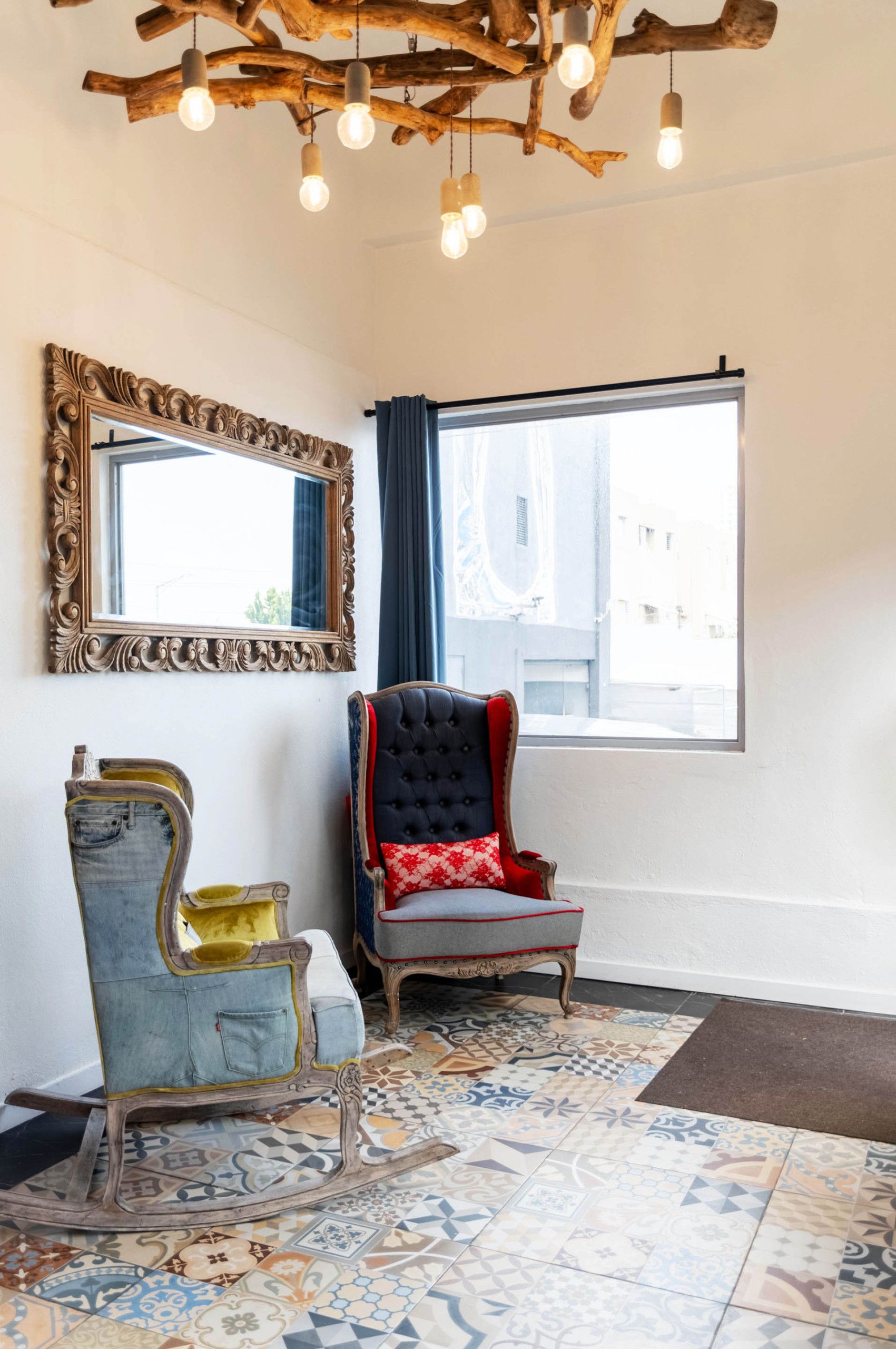 Una habitación con un espejo grande, una ventana con cortinas, un tapete estampado y dos sillas con diseños originales.
