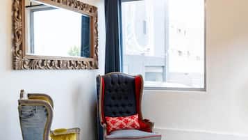 Una habitación con un espejo grande, una ventana con cortinas, un tapete estampado y dos sillas con diseños originales.