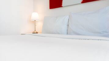 A hotel room with a bed, a nightstand, and a lamp.