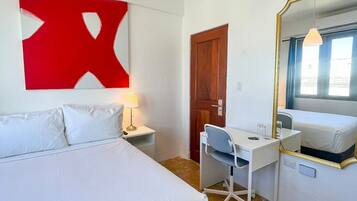 A hotel room with a bed, desk, chair, and a large mirror.