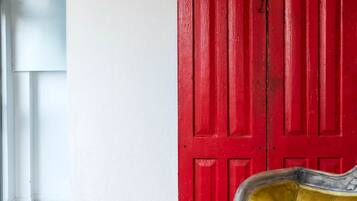 Una habitación con una puerta roja, un sillón amarillo y un suelo estampado.