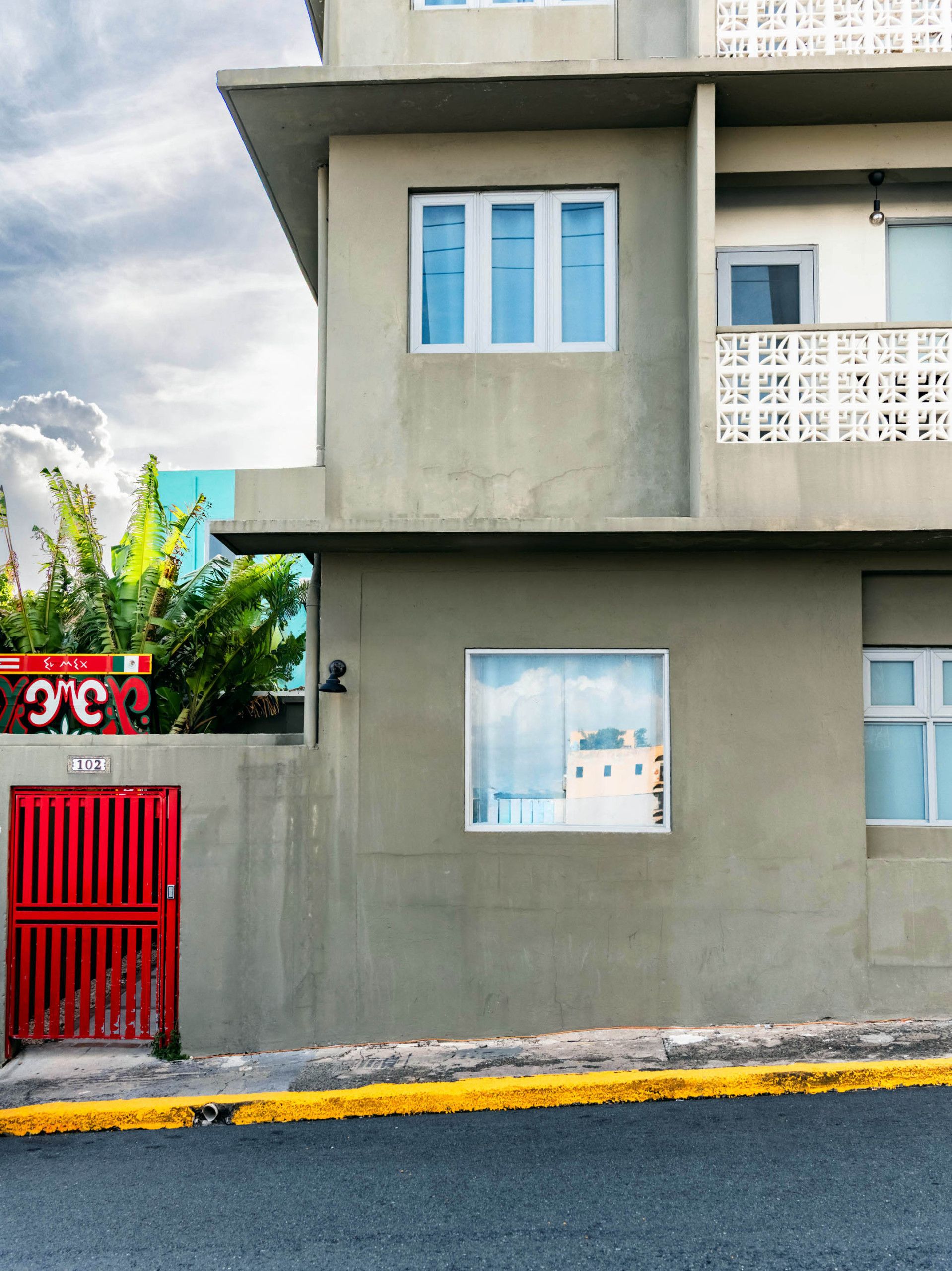 Un bâtiment moderne avec une façade en béton, une porte rouge et un marquage routier jaune.