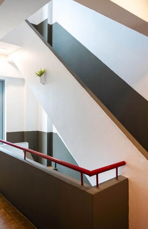 Un escalier moderne avec une rampe rouge et une plante en pot accrochée au mur.