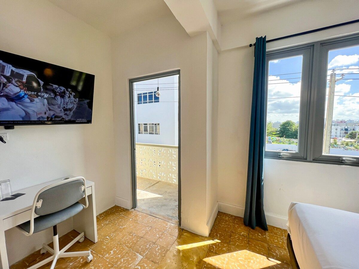 A hotel room with a bed, a desk, a television, and a window with curtains.