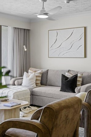 A living room with a sofa, a coffee table, and a ceiling fan. - Everlong- Palm Beach (Gold Coast)