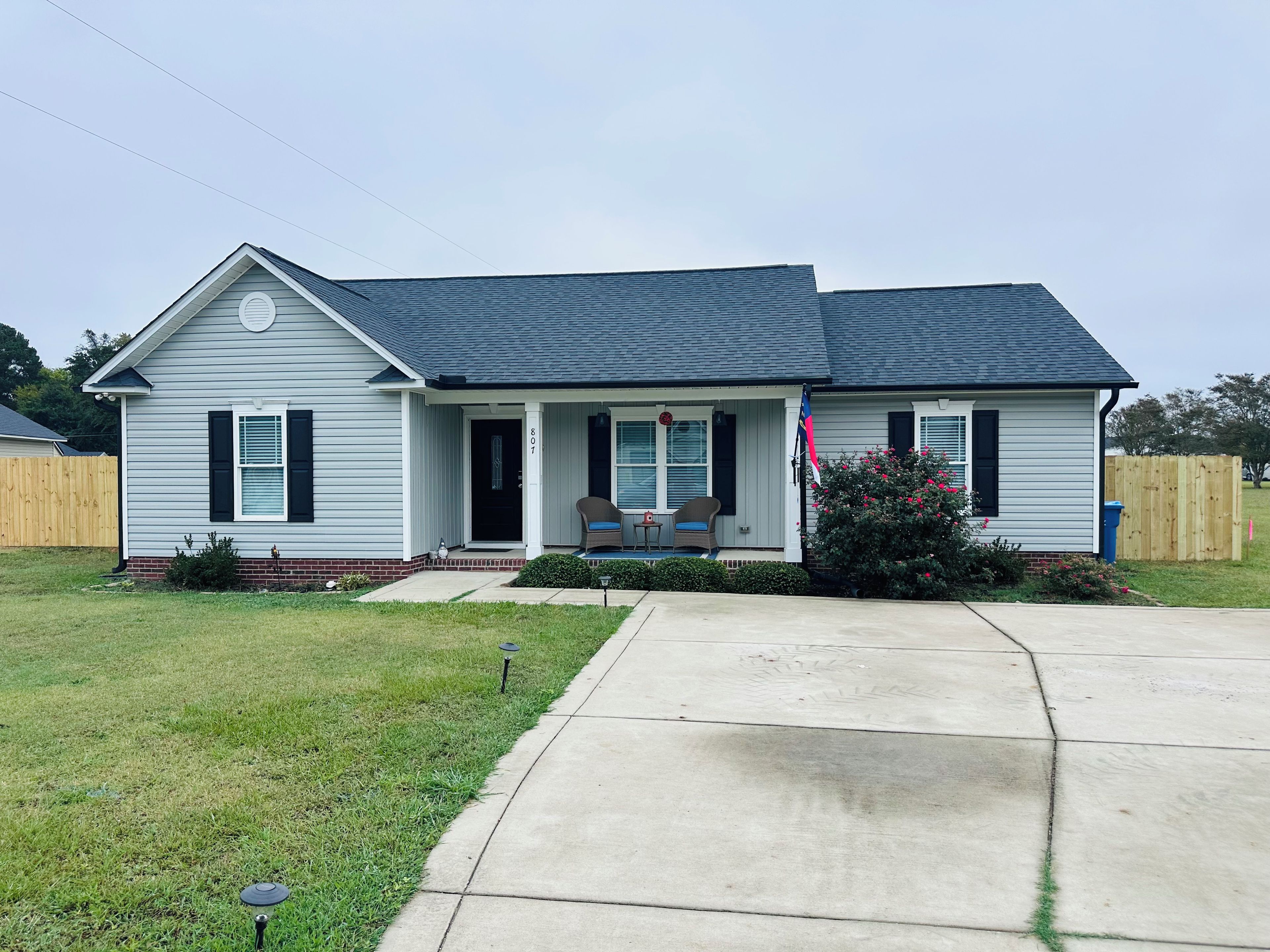 A single-story house with a front porch, a mailbox, and a flagpole.