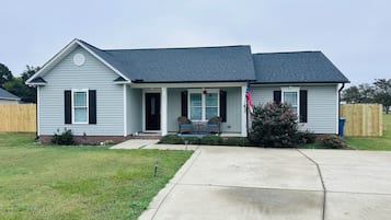 A single-story house with a front porch, a mailbox, and a flagpole.