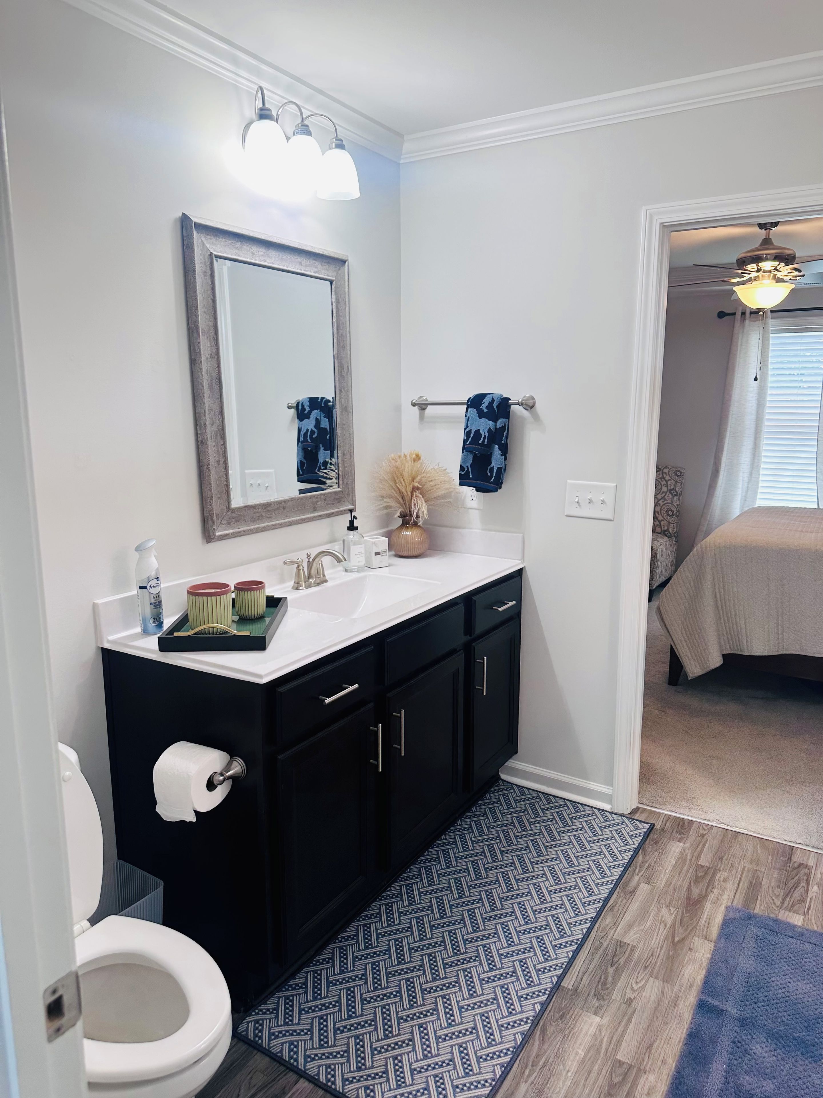 A bathroom with a white sink, black cabinets, a mirror, and a towel rack.