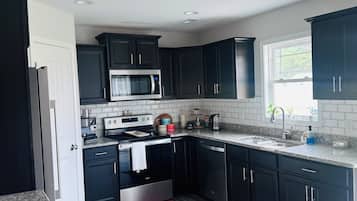 A modern kitchen with dark cabinets, a stainless steel range, and a granite countertop.