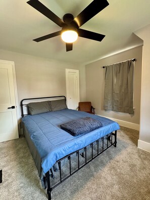 A bedroom with a bed, a ceiling fan, a window with curtains, and a door. - NEW! Stylish Stay in the Heart of Palmyra! (Palmyra)