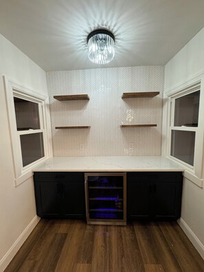 A compact kitchenette with a built-in oven, wooden shelves, and a herringbone-patterned backsplash. - NEW! Stylish Stay in the Heart of Palmyra! (Palmyra)