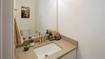 A bathroom with a beige countertop, a white sink, a mirror, and a towel rack.