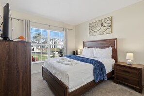 A hotel room with a bed, bedside tables, a TV, and a window with blinds. - Amazing Retreat at Lake Berkley (Kissimmee)