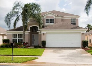 A two-story house with a garage, a front entrance, and a well-maintained lawn. - Amazing Retreat at Lake Berkley (Kissimmee)