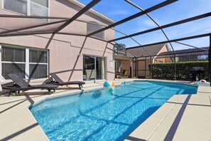 Ein Schwimmbecken mit Liegestühlen und einer überdachten Terrasse.
