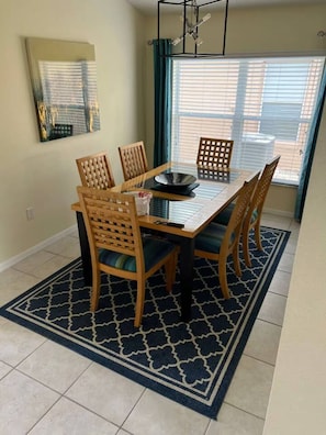 A dining area with a rectangular table, six wooden chairs, and a patterned rug. - Amazing Retreat at Lake Berkley (Kissimmee)