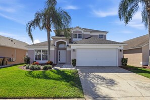 A two-story house with a garage, a front door, and a small porch. - Amazing Retreat at Lake Berkley (Kissimmee)