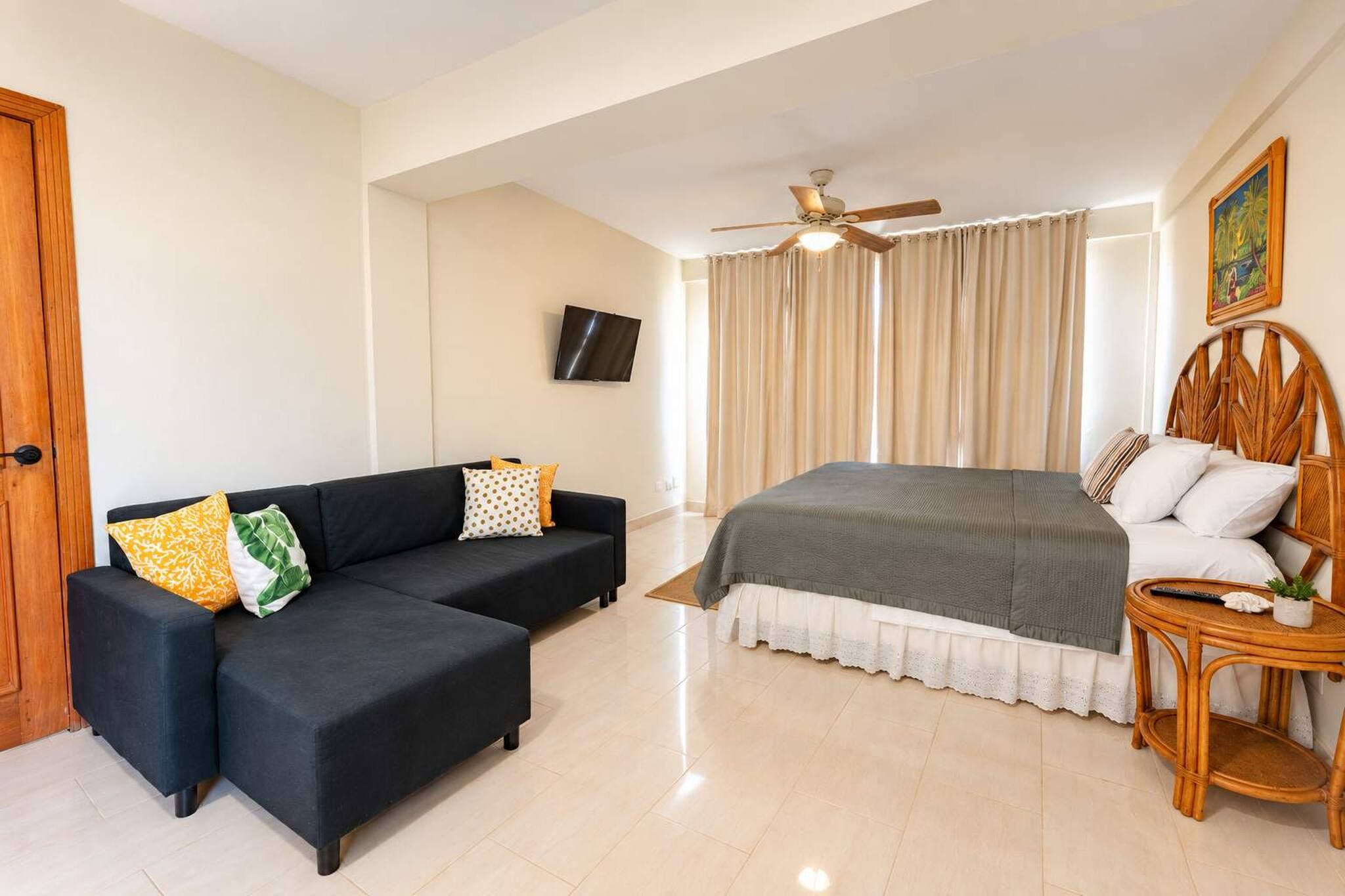Un dormitorio con cama, sofá, televisión y ventilador de techo.