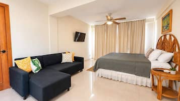 Un dormitorio con cama, sofá, televisión y ventilador de techo.